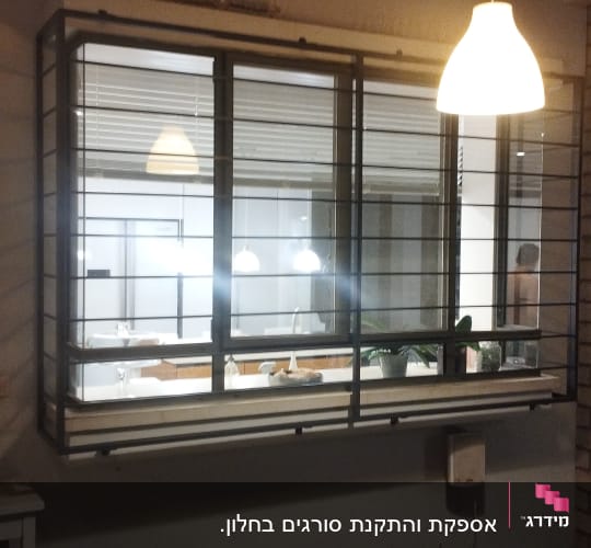 חלון עם מסגרת מתכת ומנורה תלויה